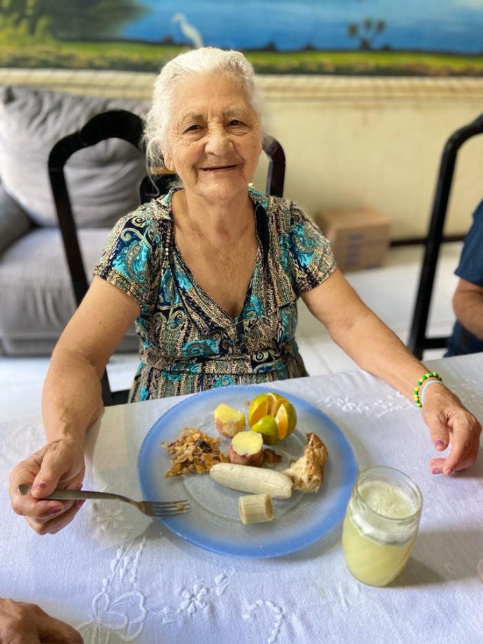 Idosa recebendo alimento do projeto Conexão do Bem da Conectel Multioperadora